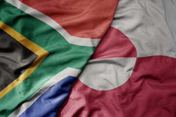 big waving national colorful flag of greenland and national flag of south africa .