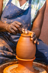 Gros plan sur les mains d'un homme qui fabrique une poterie en argile.	