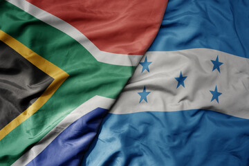 big waving national colorful flag of honduras and national flag of south africa .