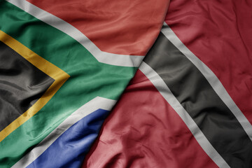 big waving national colorful flag of trinidad and tobago and national flag of south africa .