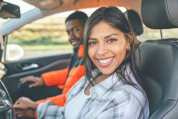 Beautiful happy young loving couple holding hands and smiling while sitting in their first car. Buy...