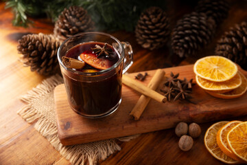Spiced wine or Christmas mulled wine with orange, cinnamon, star anise, clove, nutmeg and other ingredients on a wooden rustic table. Traditional hot drink at winter time and Christmas holidays.