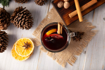 Spiced wine or Christmas mulled wine with orange, cinnamon, star anise, clove, nutmeg and other ingredients on a wooden rustic table. Traditional hot drink at winter time and Christmas holidays.