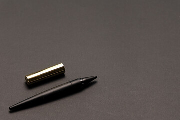 Black kajal eyeliner pencil or black crayon for make up with gold cap on the black background with...
