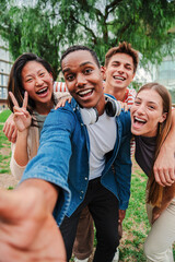 Vertical portrait of happy african american teenager laughing with his cheerful friends. Group of multiracial young student people smiling and taking a selfie together. Classmates on friendly meeting