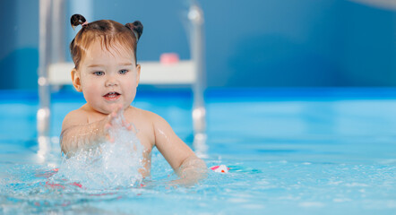 Fototapeta na wymiar Cute happy baby girl swimming with instructor in pool. Concept banner health care sport for kid
