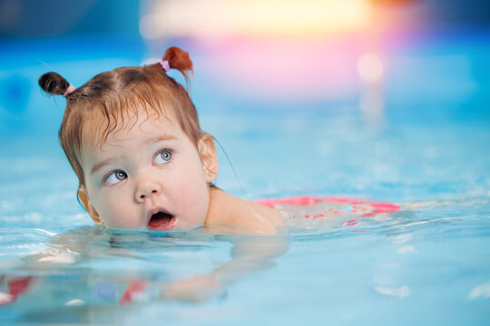 Little baby swimmer. Cute happy kid girl floating in swimming pool. Sport activity for health concept