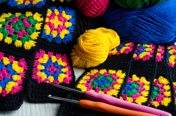Crochet texture, thread rolls and hooks. Colorful cotton granny square.