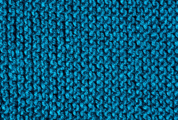 Turquoise garter stitch pattern is knitted on wool blend yarn.