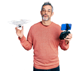 Middle age hispanic man with grey hair using drone with remote control looking at the camera blowing a kiss being lovely and sexy. love expression.