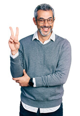 Middle age hispanic with grey hair wearing glasses smiling with happy face winking at the camera...