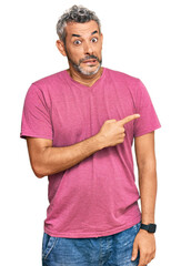 Middle age grey-haired man wearing casual clothes pointing aside worried and nervous with...