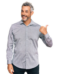 Middle age grey-haired man wearing casual clothes smiling with happy face looking and pointing to...