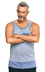 Middle age grey-haired man wearing casual style with sleeveless shirt skeptic and nervous, disapproving expression on face with crossed arms. negative person.