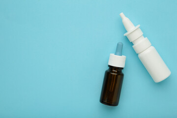 Bottles of nasal drops on blue background. Space for text
