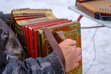 a man plays a bright harmonica on the street in winter, a street musician. An ancient musical...