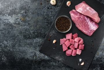 Diced raw pork meat with on slate board on black background.