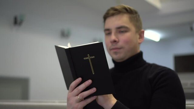 A young man reads the Bible while sitting