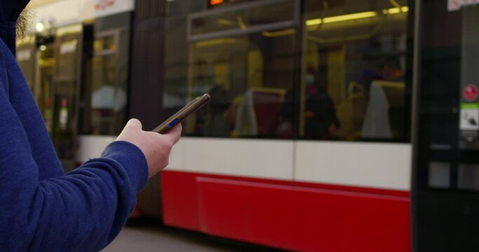 Man waiting tram, engrossed smartphone. Scene depicts urban life, with focus smartphone use. Man tram stop scrolling through smartphone, epitomizing modern connectivity. Conception technologies.