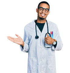Young african american man wearing doctor uniform and stethoscope showing palm hand and doing ok gesture with thumbs up, smiling happy and cheerful