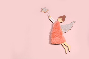 wooden angel flying behind a star on a pink background with copy space, festive background