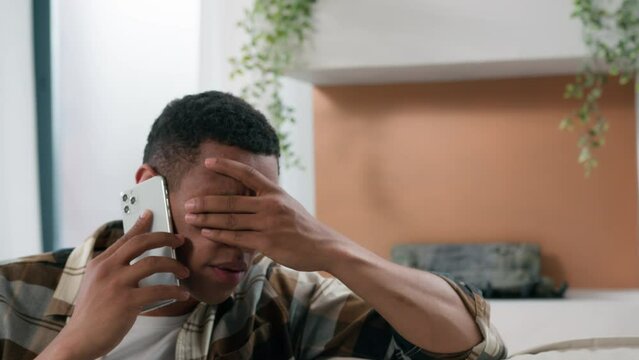 African upset worried stressed male answer cellphone call frustration guy problem sad feel stress talking mobile phone speaking smartphone at home American man hearing bad news bank reject failure