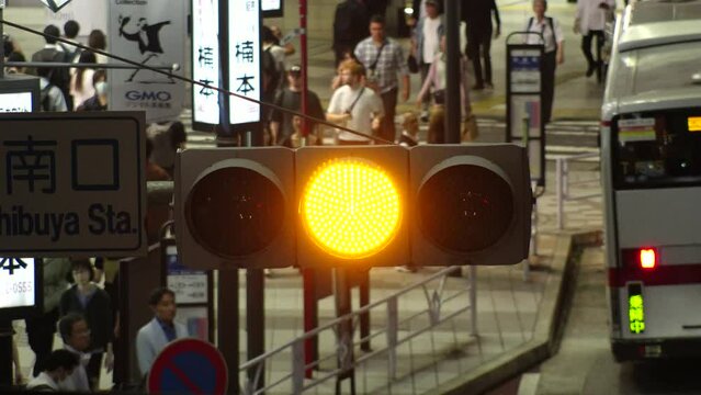 TOKYO, JAPAN - NOV 2023 : Close up shot of led traffic light at the street in night time. Crowd of people walking in background. Japanese traffic and transportation concept video in 4K.