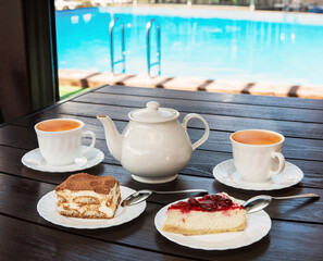 Afternoon tea set with hot tea and tasty cakes