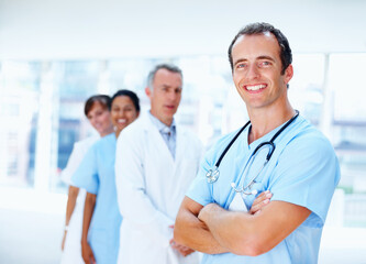 Doctors, man and arms crossed in group in clinic with staff, leader or team for healthcare services. Medic, portrait and solidarity for diversity for inclusion, women or nurses in support at hospital