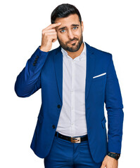 Young hispanic man wearing business jacket pointing unhappy to pimple on forehead, ugly infection of blackhead. acne and skin problem