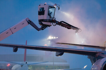 Deicing of airplane before flight. Winter frosty night and ground service at airport during...