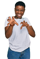 Young african american woman wearing casual white t shirt smiling funny doing claw gesture as cat,...