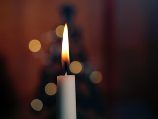 Candle at Christmas in cold winter window with bokeh lights