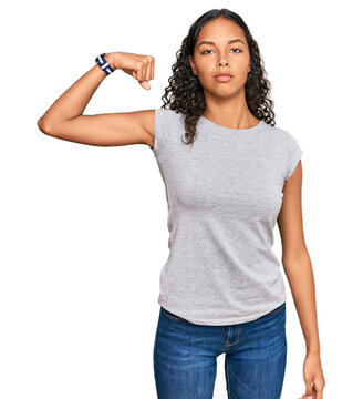Young african american girl wearing casual clothes strong person showing arm muscle, confident and proud of power