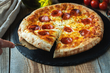A slice of hot Italian pizza with stretching cheese. Pizza pepperoni on a dark wooden background