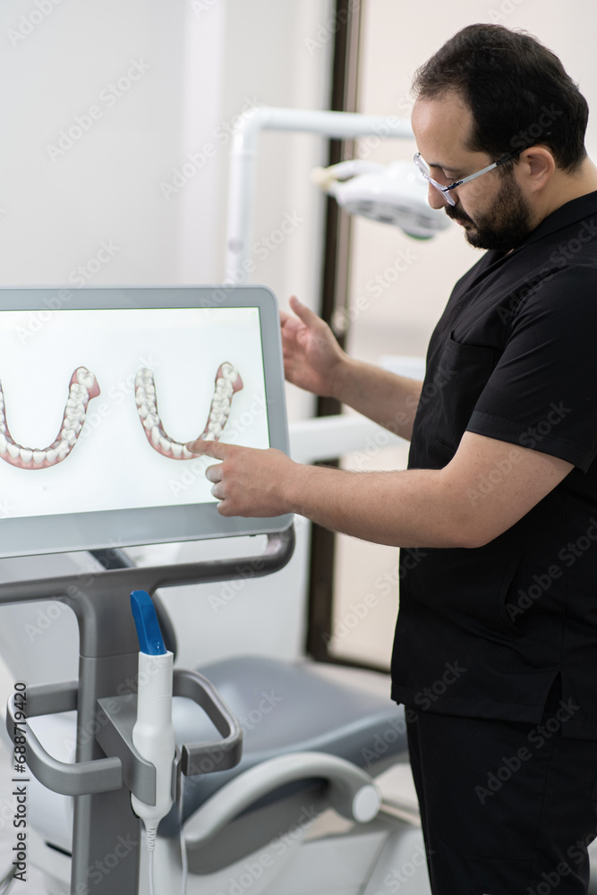 Aufkleber Bearded specialist in black uniform pointing to jaws models on computer screen using alternative teeth treatment methods in dental clinic oral cavity examination