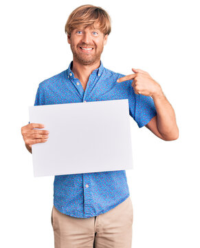 Handsome caucasian man with beard holding sale poster pointing finger to one self smiling happy and proud