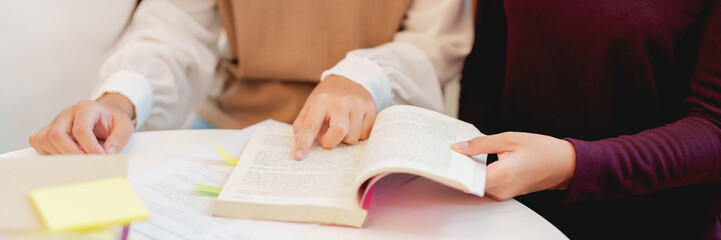 two college students reading on book learning together .