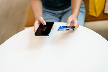 Close up hands using credit card for online purchasing on smartphone .
