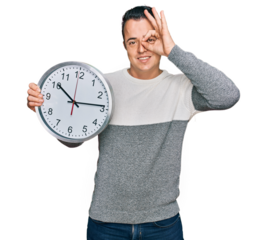 Handsome young man holding big clock smiling happy doing ok sign with hand on eye looking through fingers