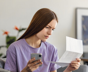Woman scrutinizes household expenses, utility bills, bank statements, taxes or bank account balance...