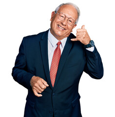 Senior man with grey hair wearing business suit and glasses smiling doing phone gesture with hand and fingers like talking on the telephone. communicating concepts.
