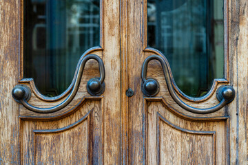 Dark old brown doors with bronze handles and glass. Wooden door with windows with street reflection, closeup