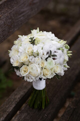 Wedding bouquet with white flowers on a wooden stairs. Bouquet with ranunculus, lisianthus, freesia and cotton flowers.