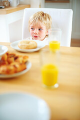 Kid, breakfast and bagel at home in the morning with food, smile and happy from eating. Family, dinner table and hungry young child with meal for health and nutrition in a house with orange juice