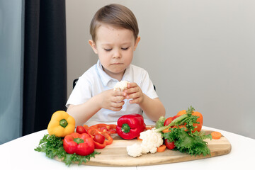 sad boy looking at cauliflower, Nutrition healthy eating habits for kids concept. Children do not like to eat vegetables. Little boy refuses to eat healthy food.