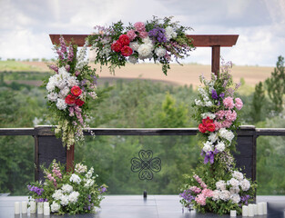 Wedding arch in the garden at open air. Wooden flower arch. Trendy wooden arch decorated with flowers.