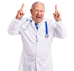 Senior handsome grey-haired man wearing doctor coat and stethoscope shouting with crazy expression doing rock symbol with hands up. music star. heavy music concept.