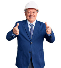 Senior handsome grey-haired man wearing suit and architect hardhat success sign doing positive gesture with hand, thumbs up smiling and happy. cheerful expression and winner gesture.
