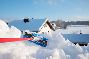 remove a lot of snow from the roof window with the snow shovel. sunny blue sky - obrazy, fototapety, plakaty